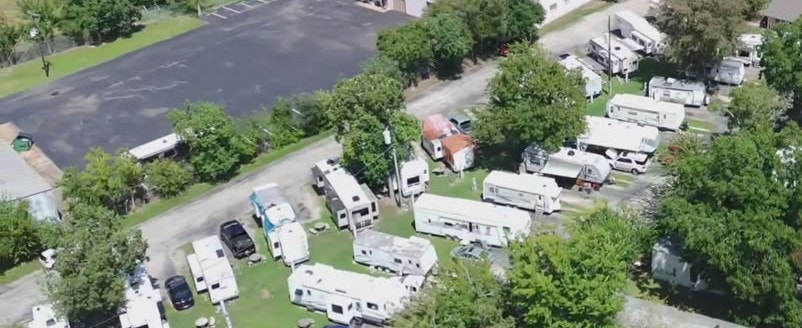 Close aerial view of RV sites with fifth-wheels and travel trailers parked on grass
