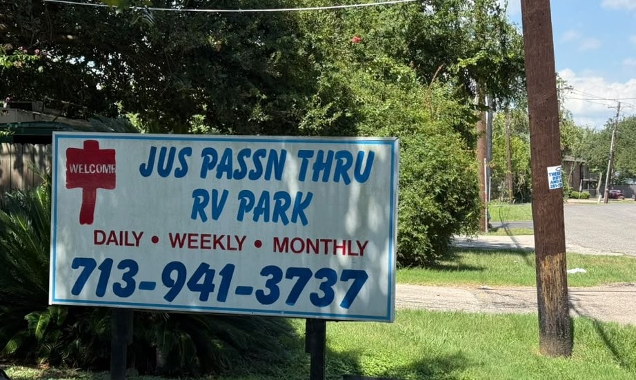 Jus Passn Thru RV Park roadside sign showing daily, weekly, and monthly rates and phone number